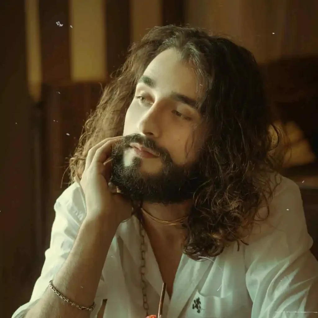 A man with long hair wearing a white shirt, featuring a stylish men's long curly hairstyle.