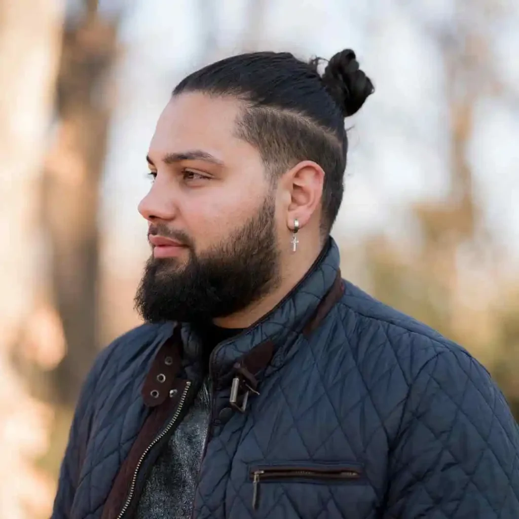 A man with a bun in his hair, showcasing a stylish men’s hairstyle with an undercut.