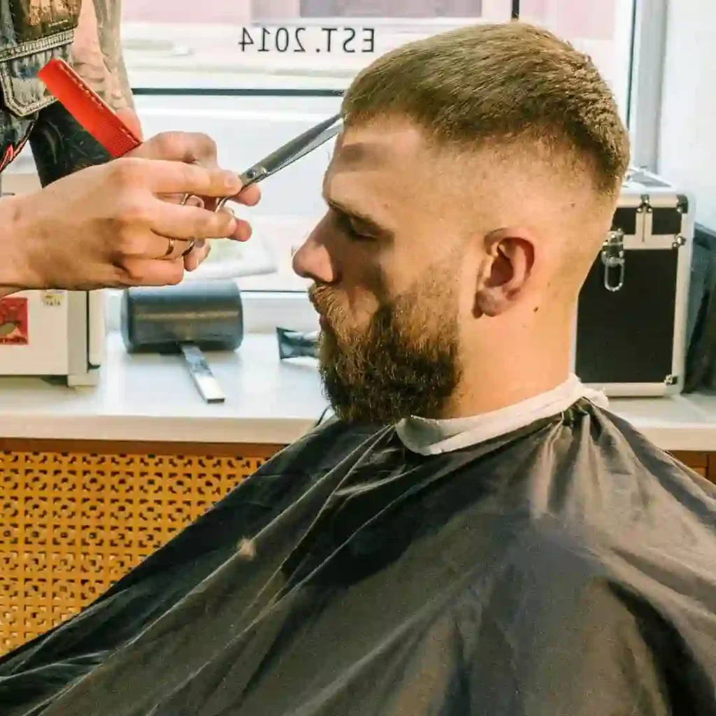 A barber cutting a client's hair with scissors in a salon, focusing on a men’s hairstyle undercut.