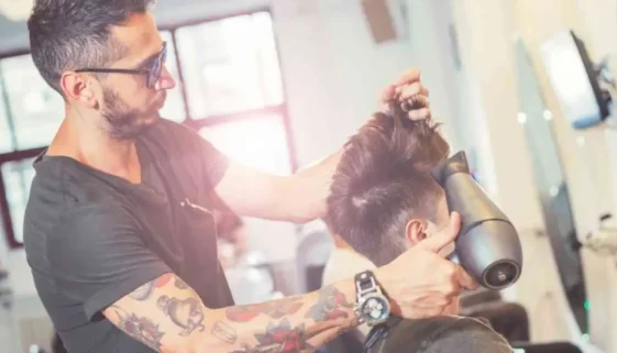 A man getting his hair cut at a barber shop, highlighting modern men hairstyles undercut.