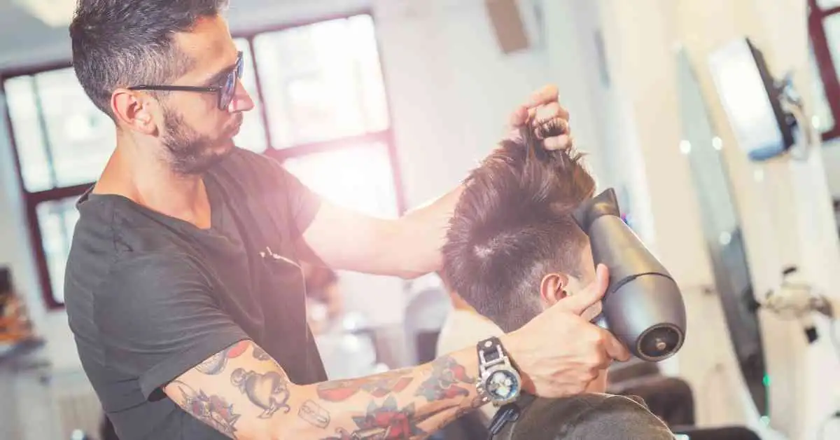 A man getting his hair cut at a barber shop, highlighting modern men hairstyles undercut.