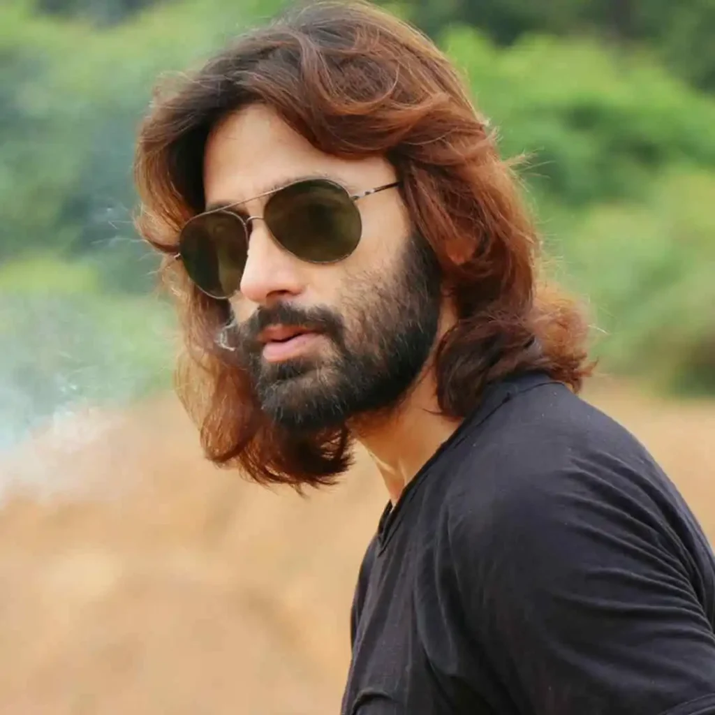 a man with long hair and sunglasses smoking a cigarette