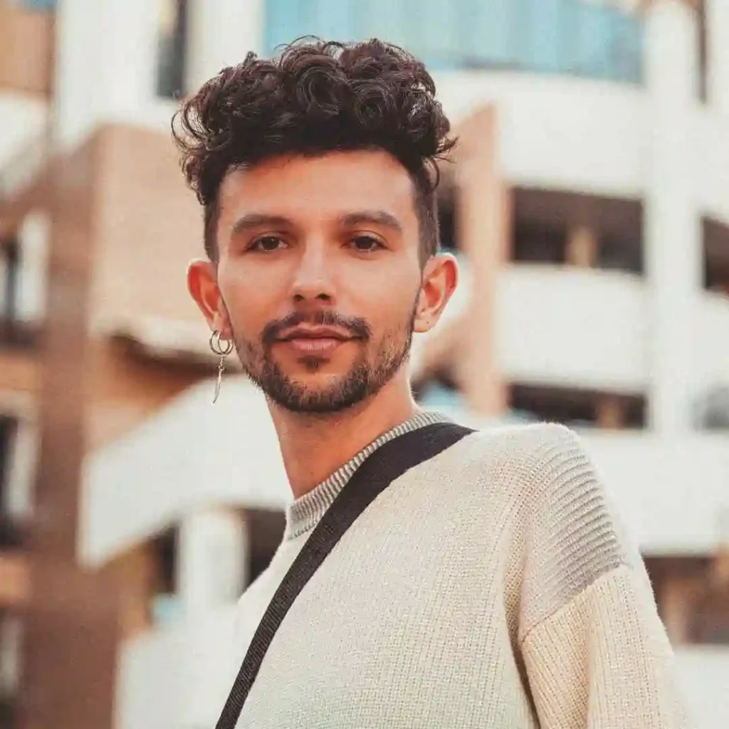 a man with curly hair wearing a sweater