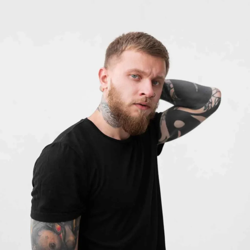 a man with a beard and tattoos on his arm