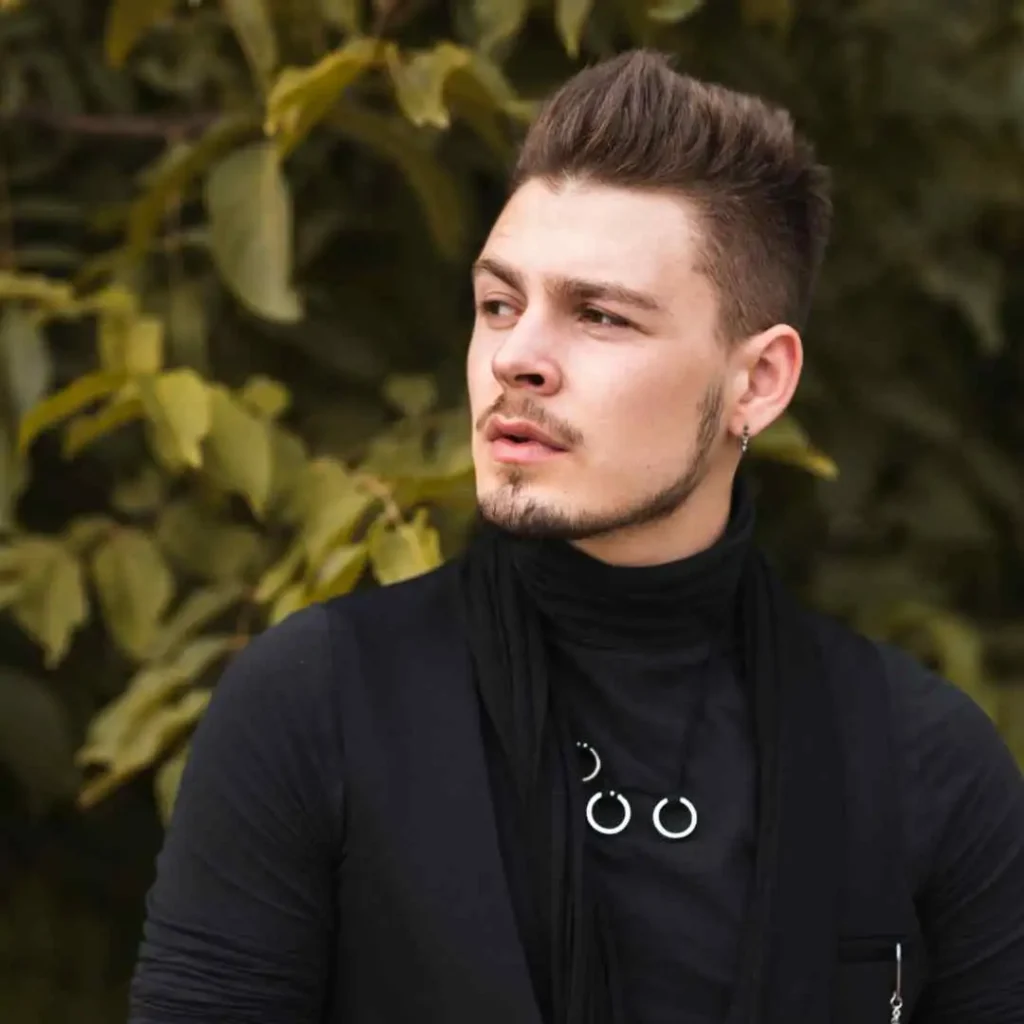 A man wearing a black shirt and a black scarf, showcasing a stylish monochrome look. All men's fashion outfits.