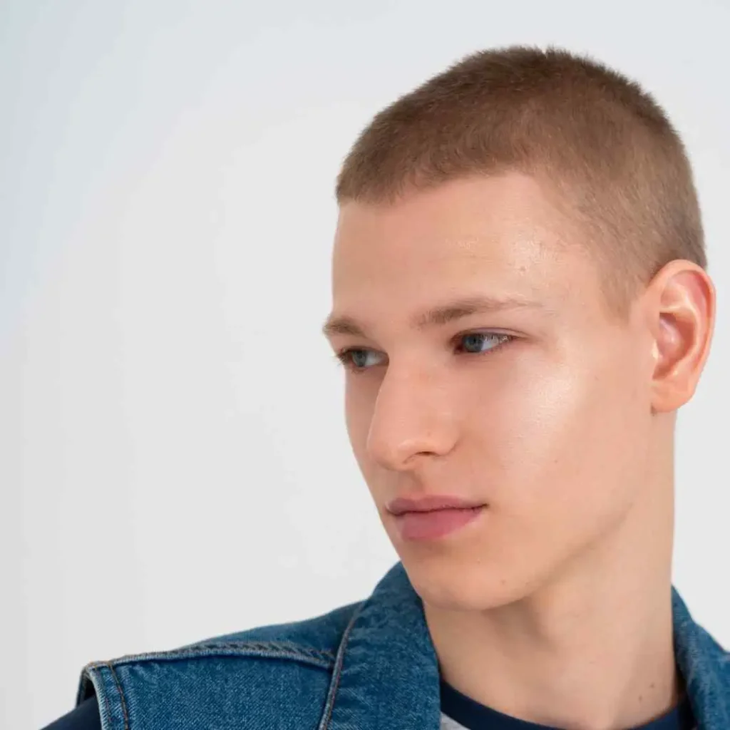 a man with a shaved head wearing a denim jacket