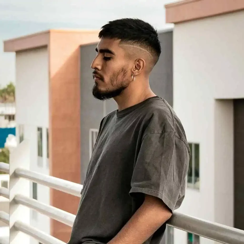 Person in a gray t-shirt leaning on a railing with buildings in the background.