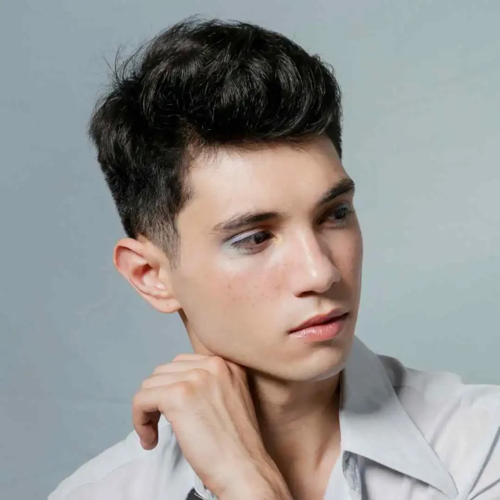 Person in a light shirt pondering, with a hand on chin, against a gray background.