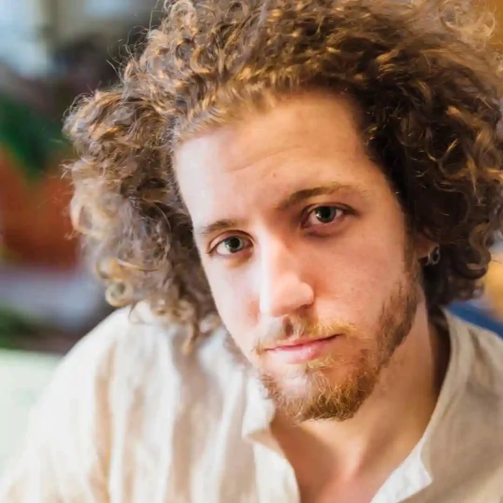 A close-up of a person with curly hair, showcasing haircuts for men with diamond face.