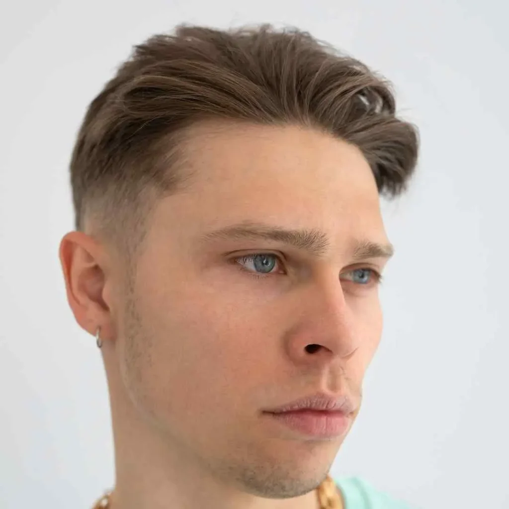 Person with a modern haircut and an earring against a white background.