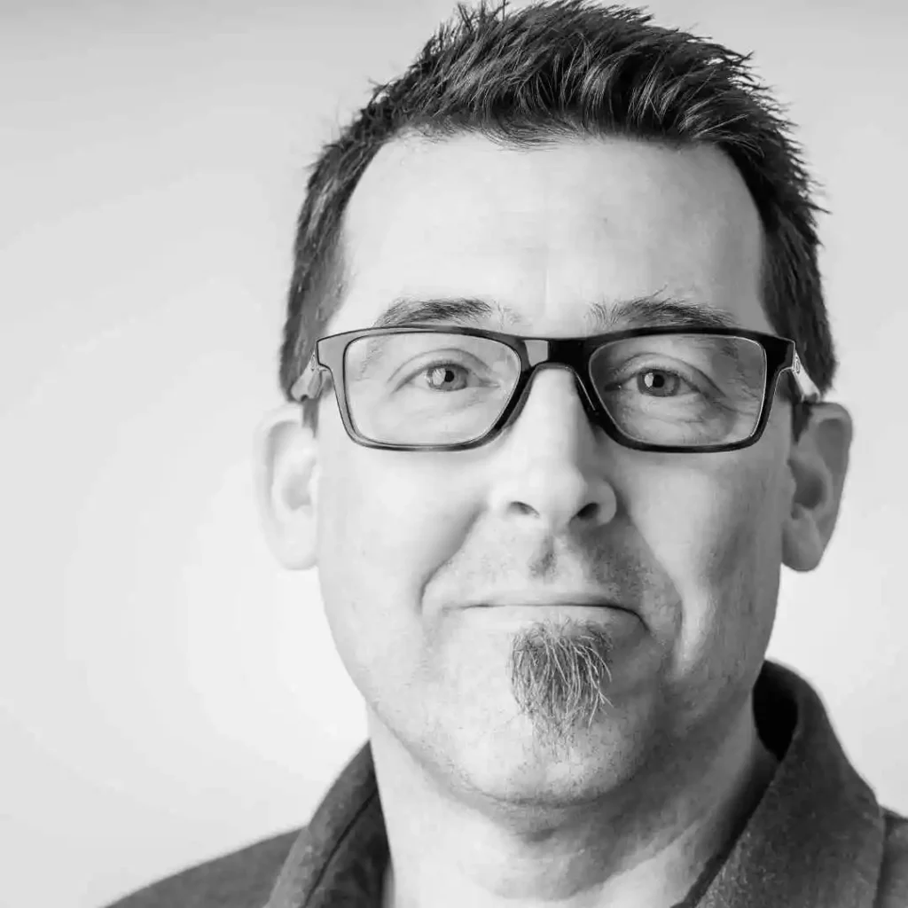 A black and white photo of a man wearing glasses, showcasing haircuts for men with diamond face.