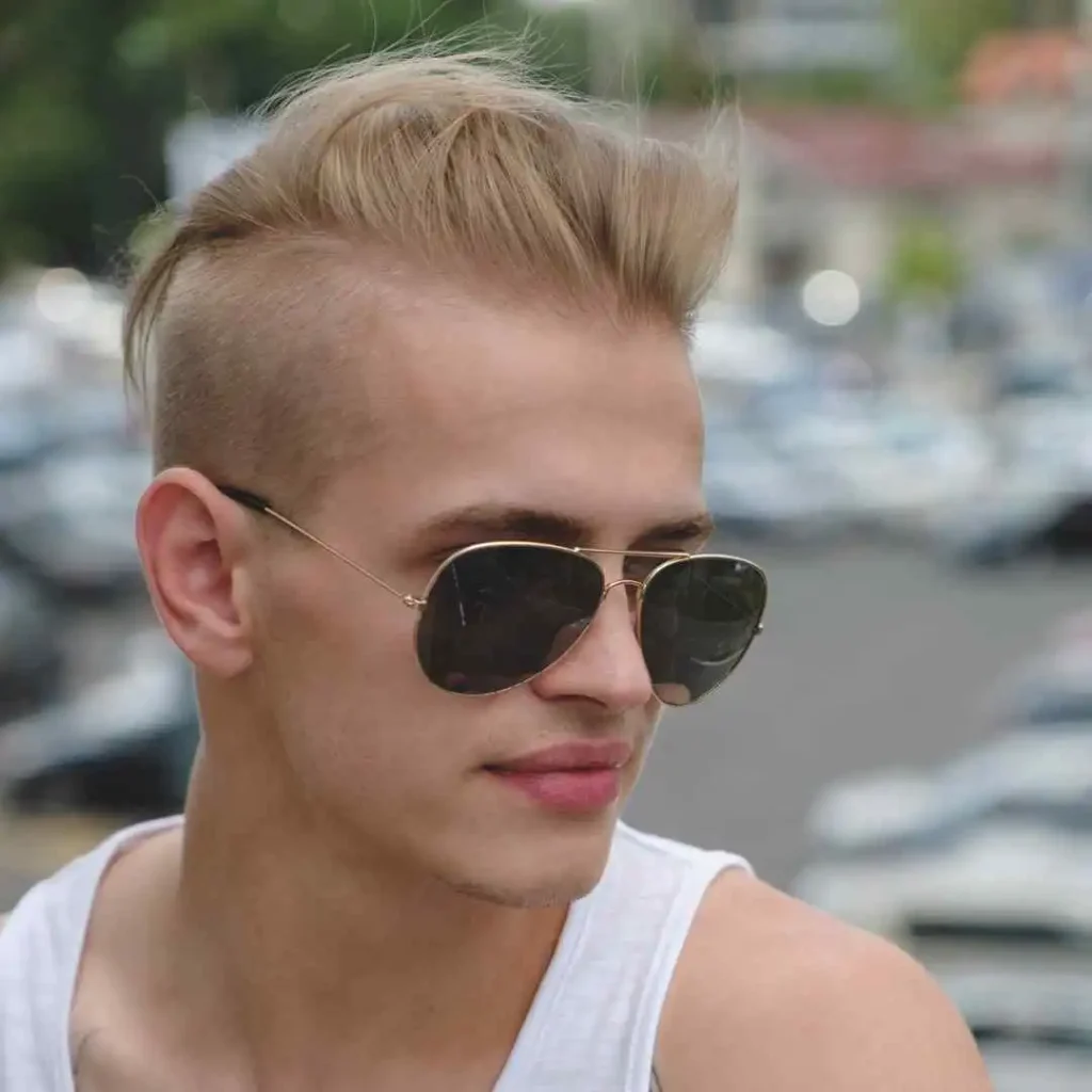 Person with a modern undercut hairstyle and sunglasses, outdoors, showcasing a trendy Mohawk men hairstyle with a bold and edgy look.