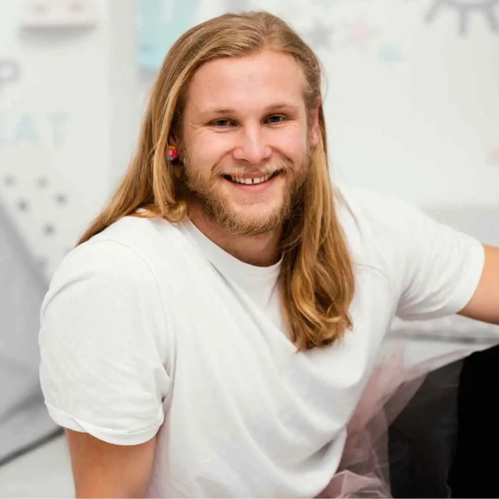 A man with long hair and a white shirt, showcasing curtain hair.