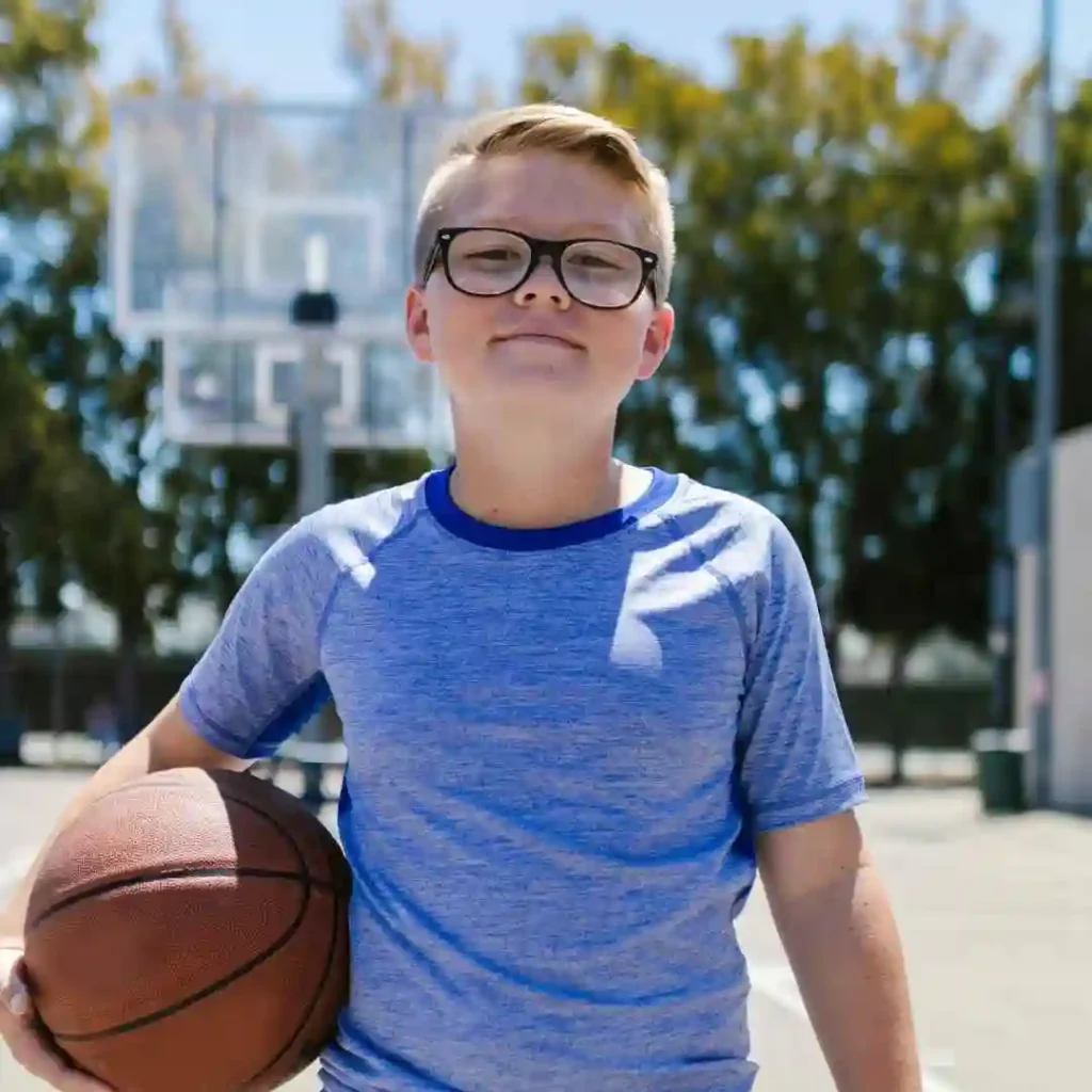 A person in a blue shirt holding a basketball on an outdoor court.