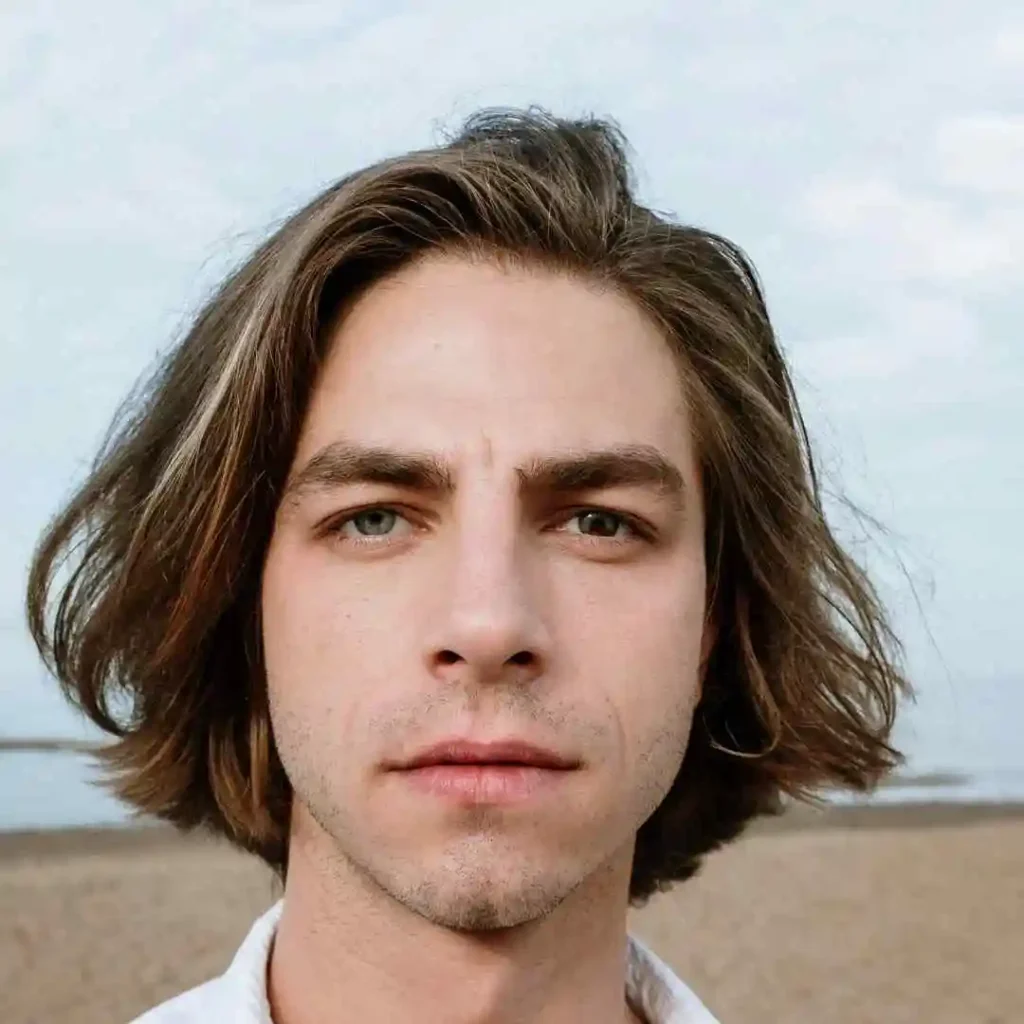 Person with shoulder-length hair on a beach, face not visible, showcasing men hairstyles for oval face.