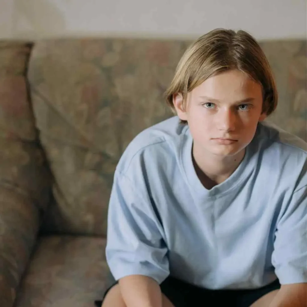 Person in a blue shirt sitting on a floral couch.