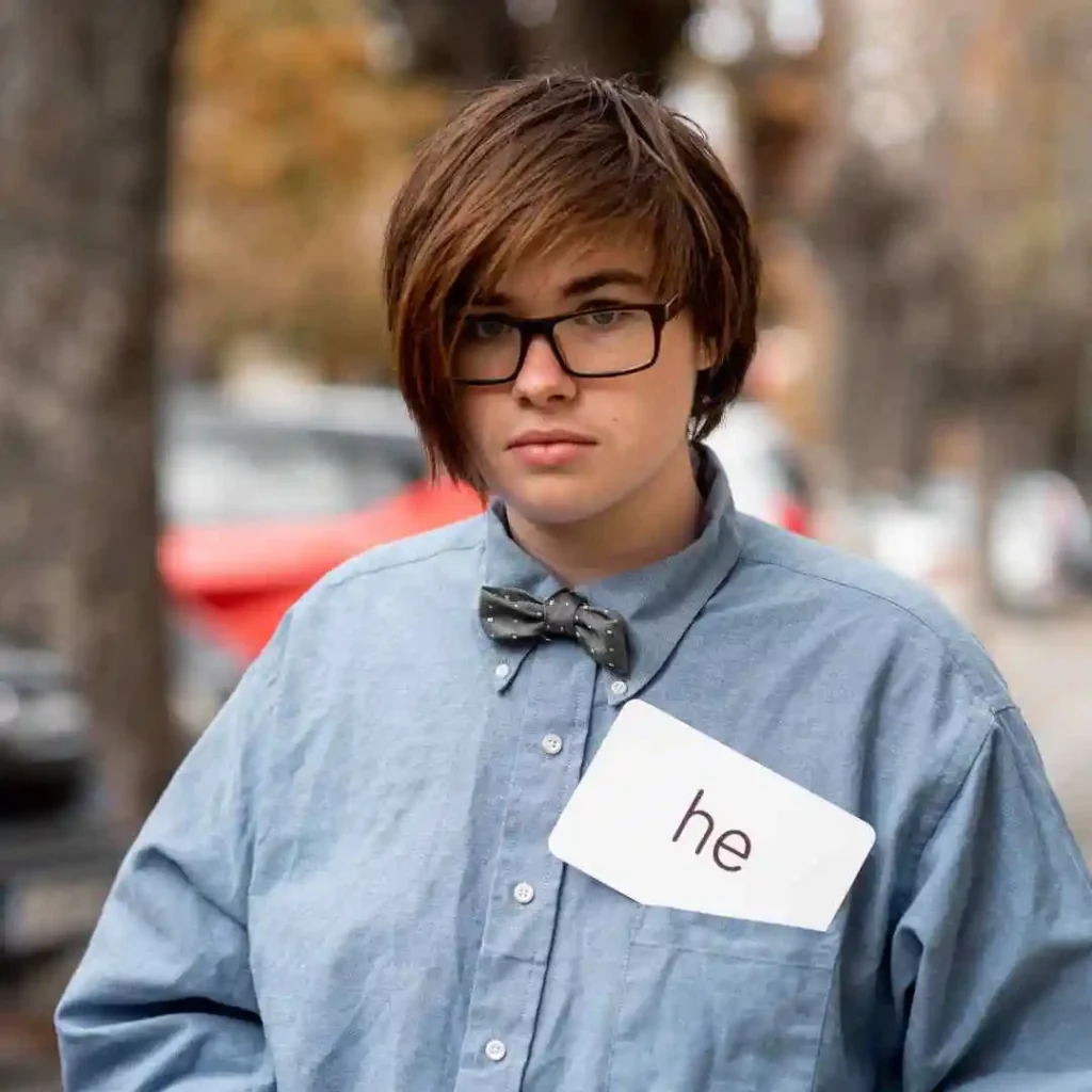 Person wearing a bow tie and a name tag with "he" on a shirt.