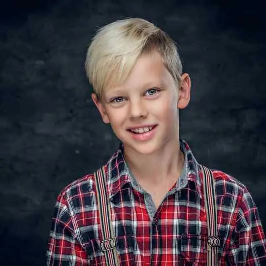 Person in red plaid shirt with suspenders against a dark background.