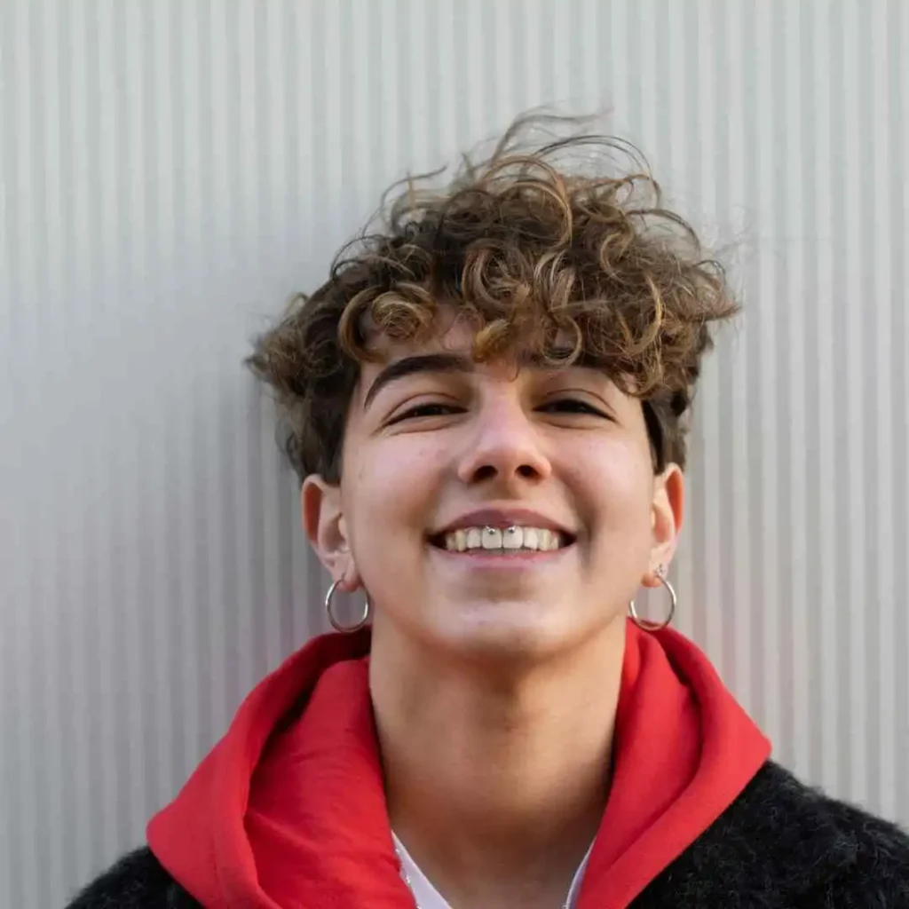 A woman with curly hair wearing a red hoodie, showcasing haircuts for men with diamond face.