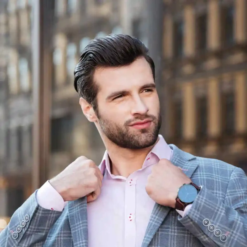 A man in a suit adjusting his tie, showcasing haircuts for men with diamond face.