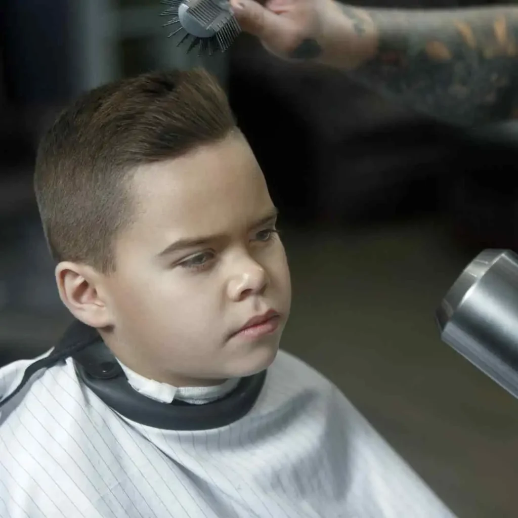 Person getting a haircut with a hairdresser's hand holding a comb above their head.