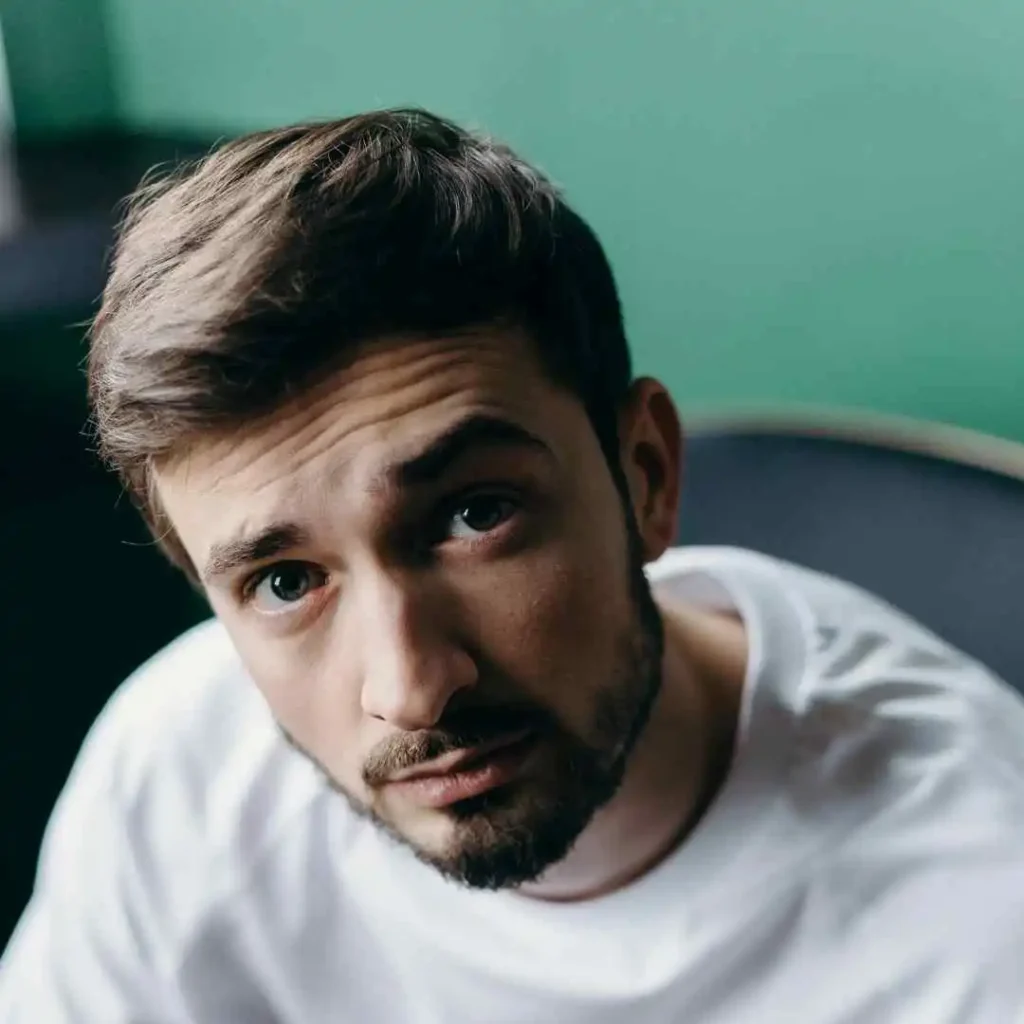 A man in a white t-shirt looking at the camera, showcasing haircuts for men with diamond face.