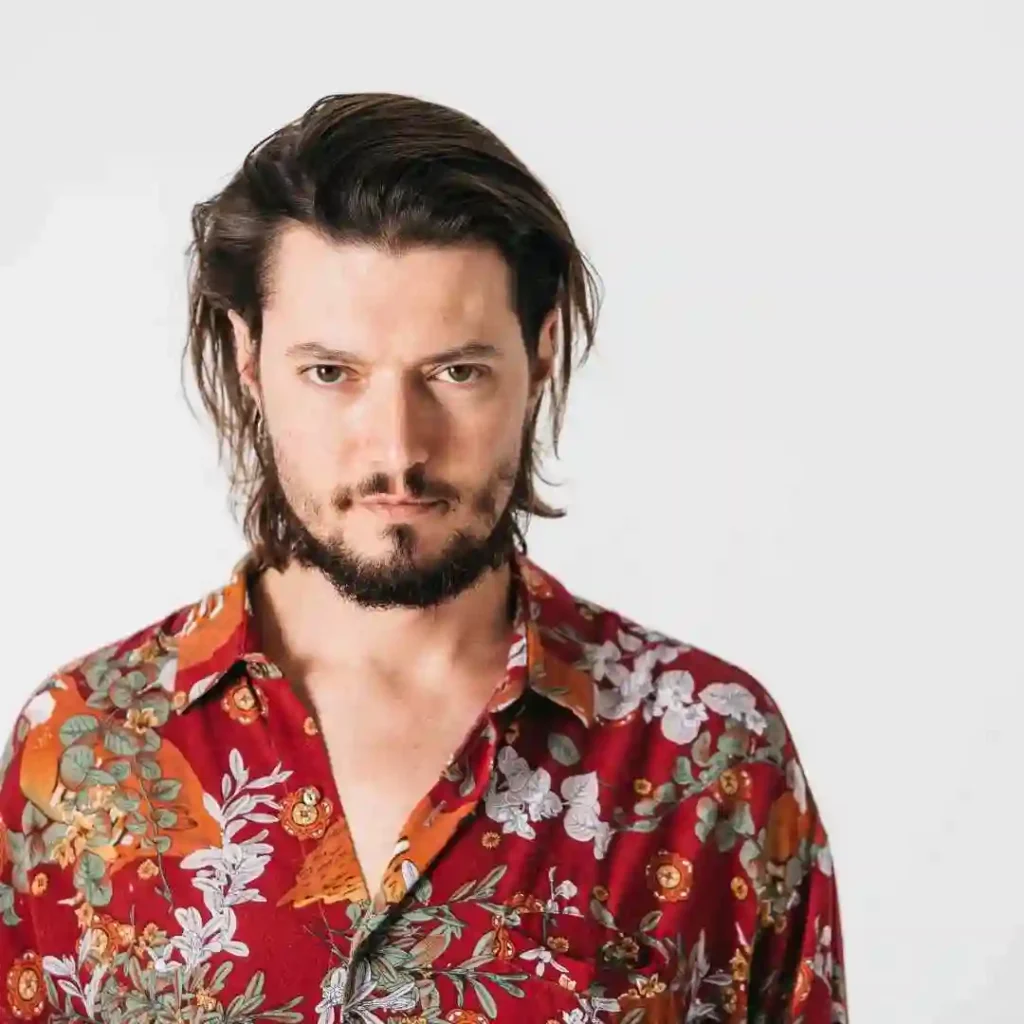 A man with long hair and a beard wearing a red shirt, showcasing haircuts for men with diamond face.