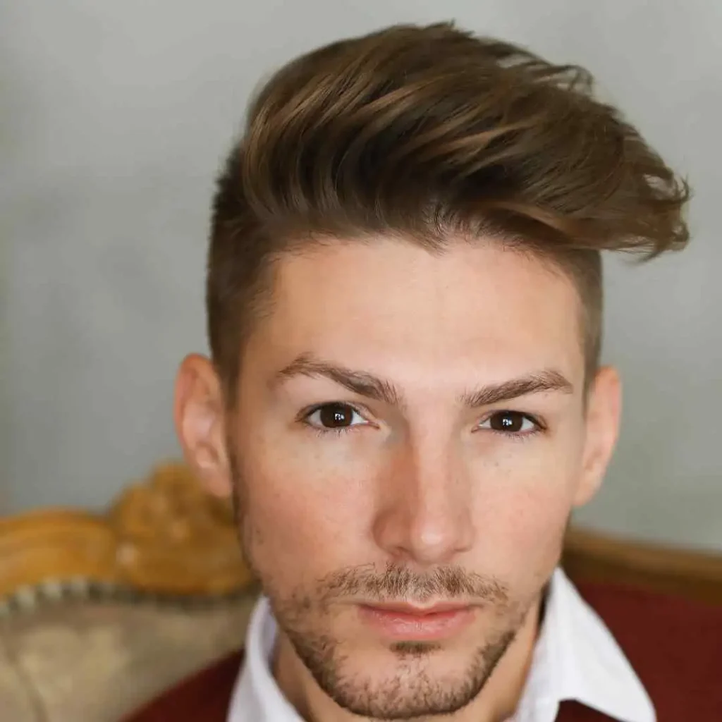 Stylish swept-back brown hair above a white shirt collar.