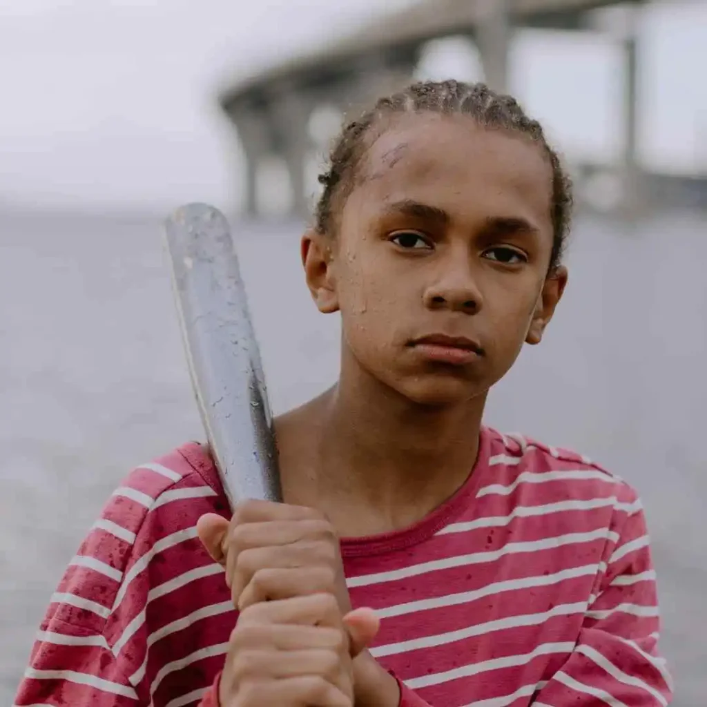 Person in a striped shirt holding a baseball bat, with a blurred background.