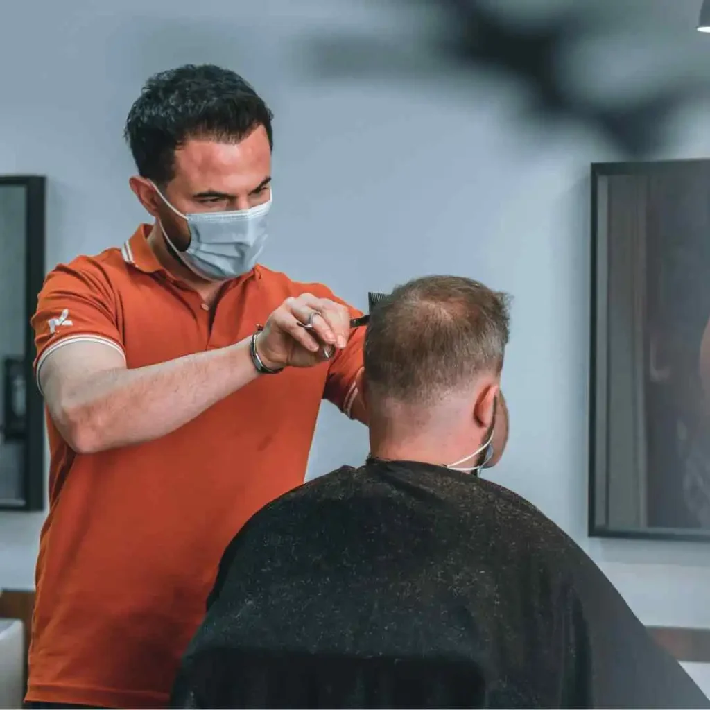 A man getting his hair cut by a barber, showcasing haircuts for men with diamond face.