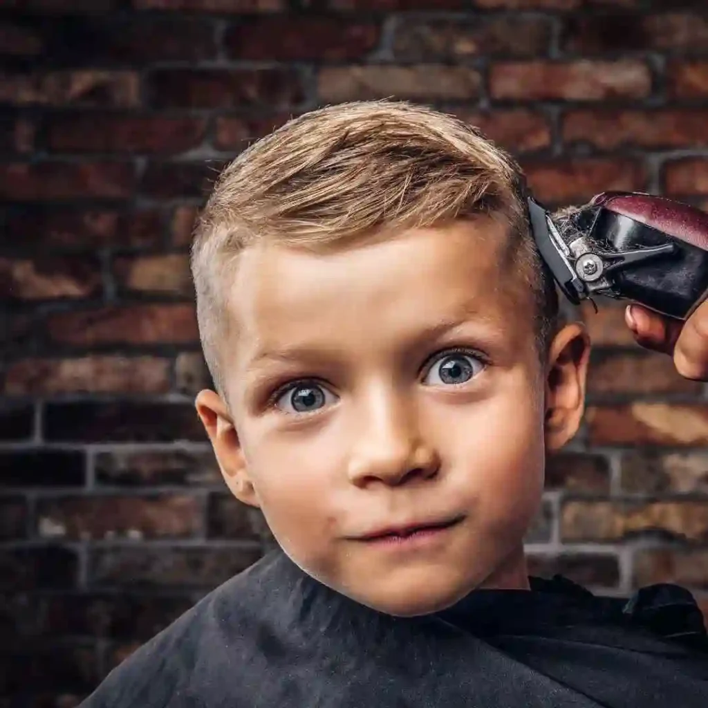 Teen Boy Haircuts style, person getting a haircut with electric clippers against a brick wall background.