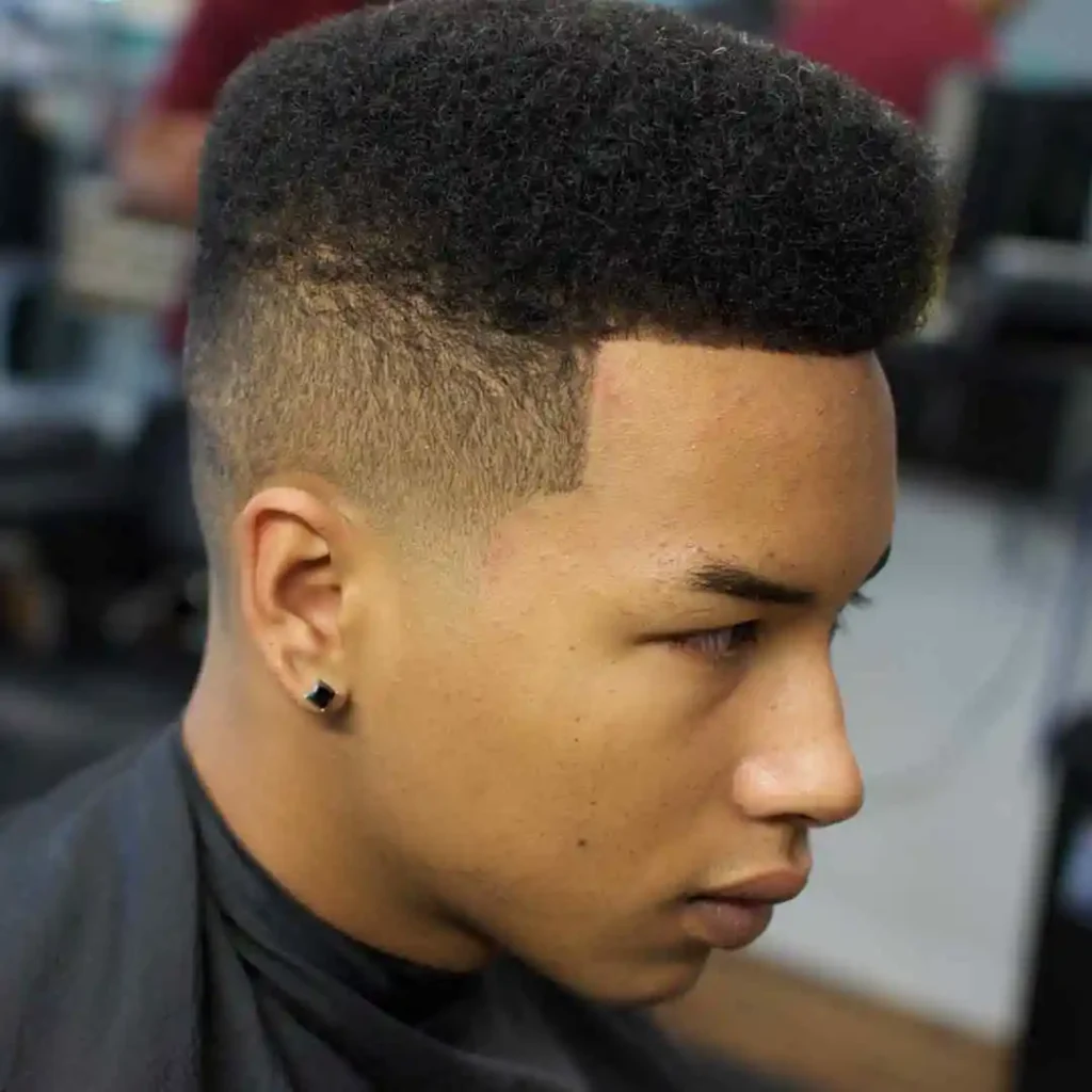 A person showcasing a high-top fade hairstyle with the sides buzzed short.