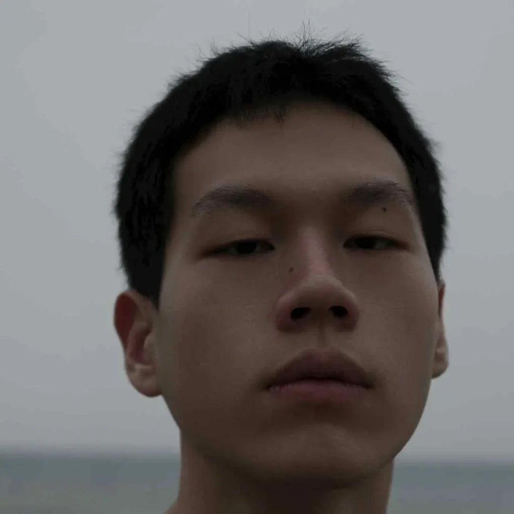 A close-up of a person near the ocean, showcasing haircuts for men with diamond face.