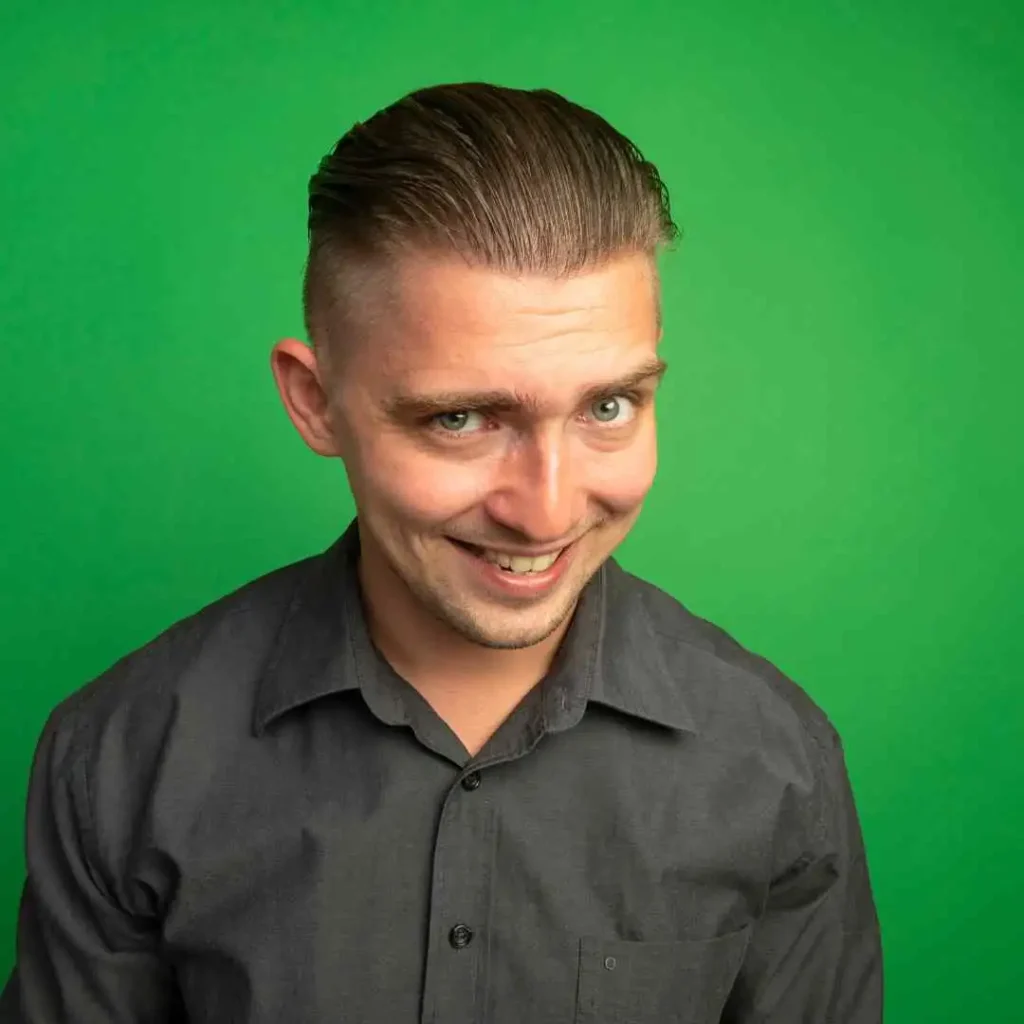 A person with MEN HAIRSTYLES QUIFF, wearing a black button-up shirt, stands against a vibrant green background, looking directly at the camera.