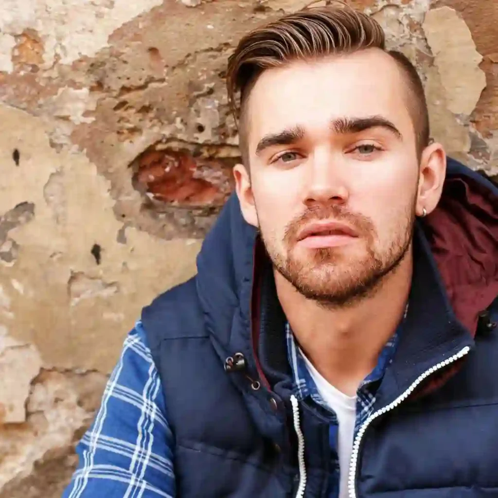 a young man leaning against a wall
