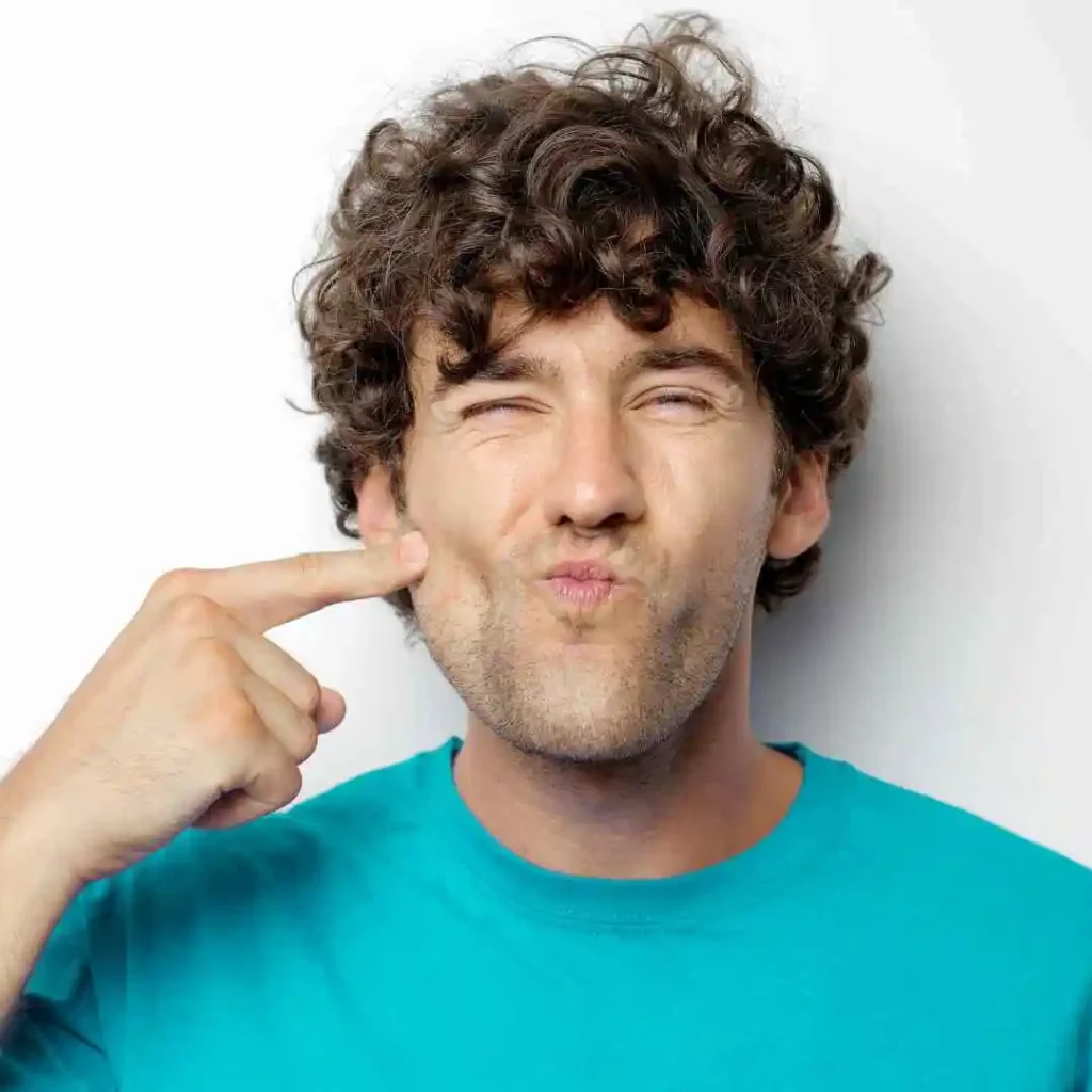 A person wearing a turquoise shirt points to their ear, illustrating a gesture of listening or signaling. White background.