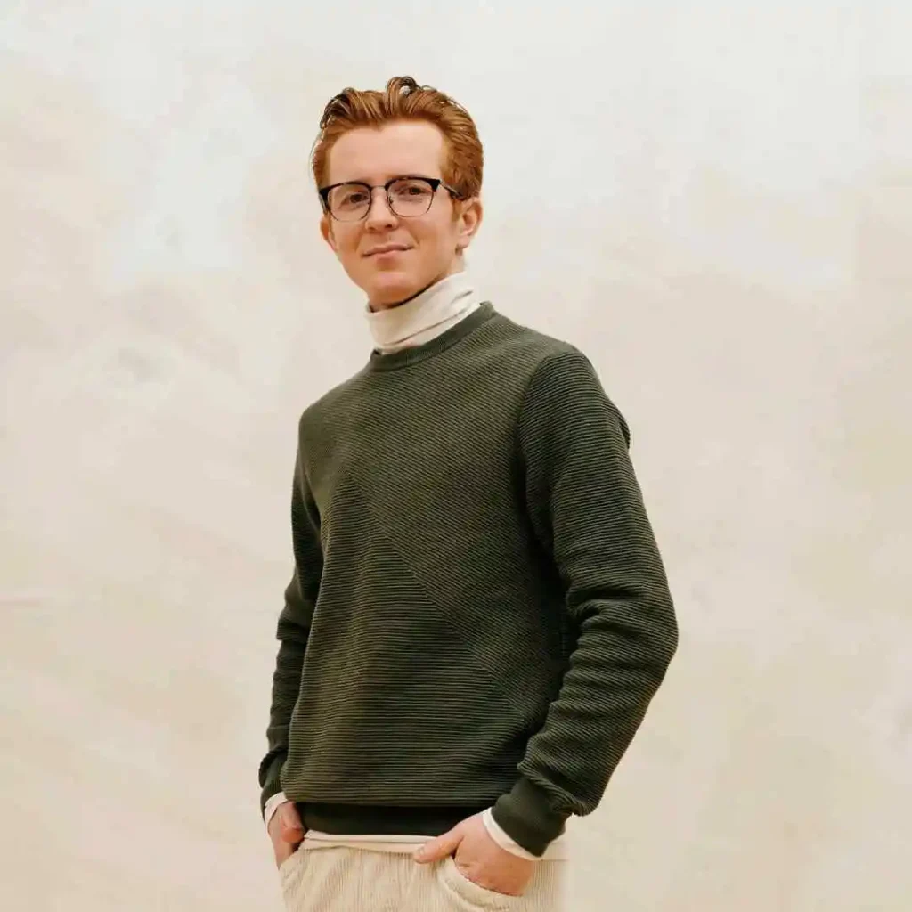 52 Mid-Length Hairstyles for Men- A Comprehensive Guide. 4 A man wearing glasses and a sweater, with a men's medium length hairstyle.