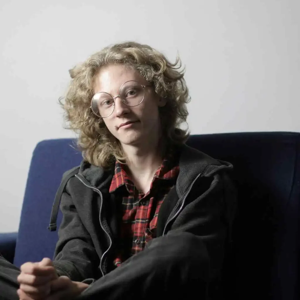 52 Mid-Length Hairstyles for Men- A Comprehensive Guide. 7 a young man sitting on a blue couch