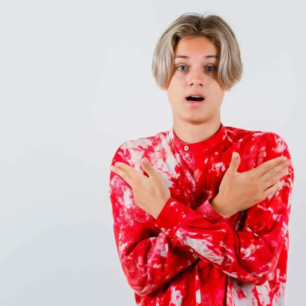 Person in a red tie-dye shirt crossing arms over chest against a white background.