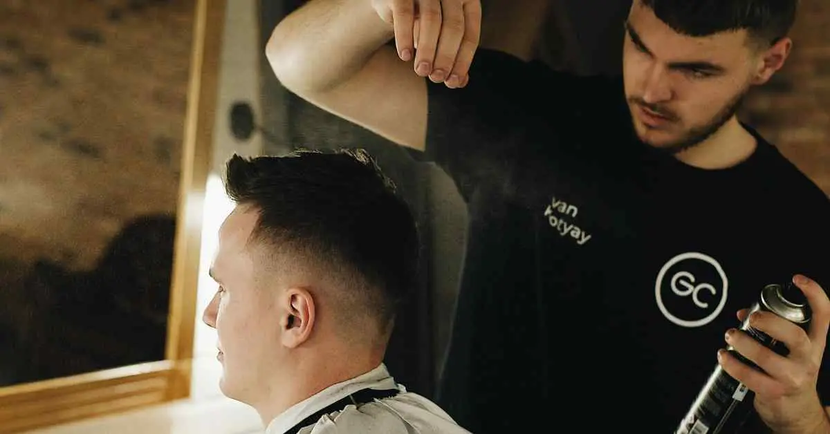 A hairstylist applying spray on a client's buzz cut in a salon, showcasing a popular men’s hairstyle.