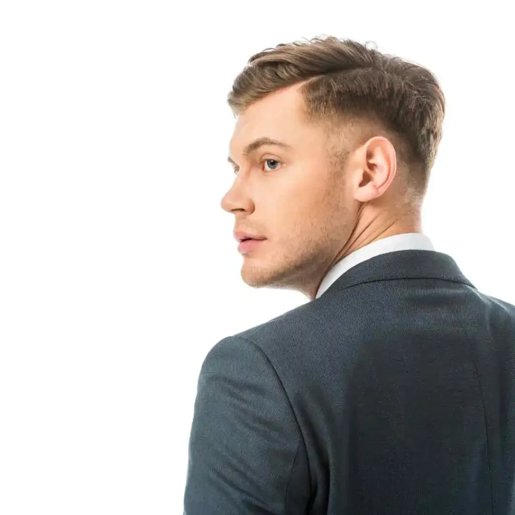 A man wearing a dark suit and white shirt stands with his back to the camera, showcasing a professional appearance against a white background.