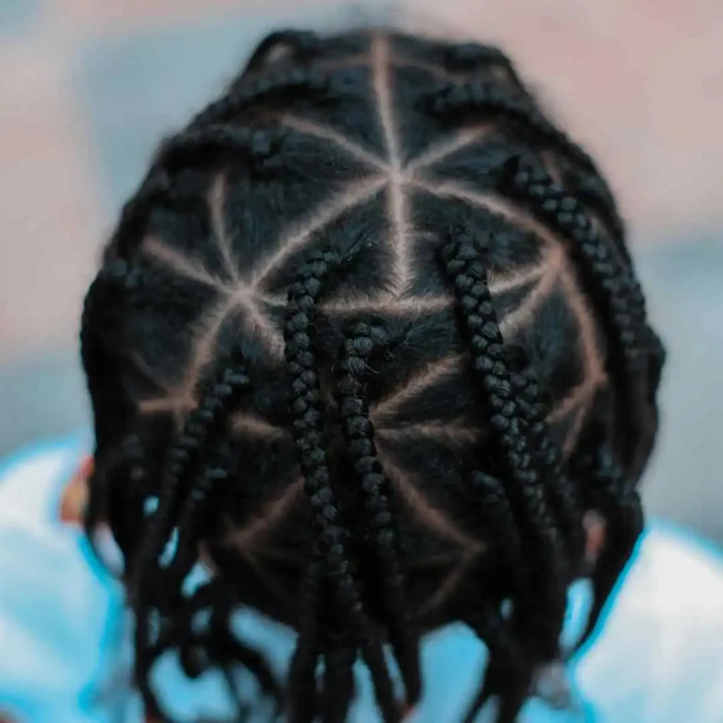 The Ultimate Guide to Men Hairstyles Cornrow- Sizzling Styles of Braided Looks 7 Close-up of a child's head showcasing intricate, neatly braided hair styled in a geometric star pattern, representing a MEN HAIRSTYLE CORNROW, against a blurred background.