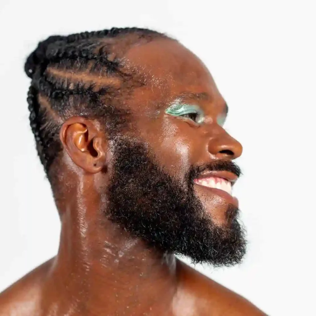 A close-up of a person with intricate MEN HAIRSTYLE CORNROW braids and a glistening neck, set against a plain white background.