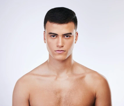 A bare-chested individual with short dark hair poses against a soft white background, showcasing a clean and simple aesthetic that highlights trendy men hairstyles Indian style.