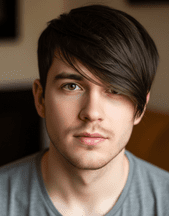 A young man with a burst fade hairstyle, wearing a grey shirt